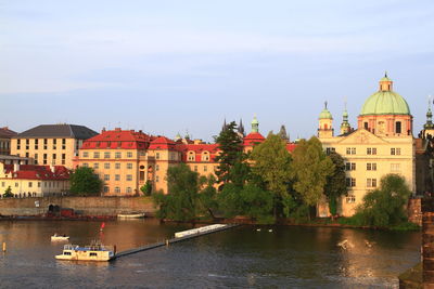 Buildings by river against sky in city