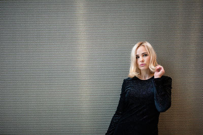 Portrait of beautiful woman standing against metal wall