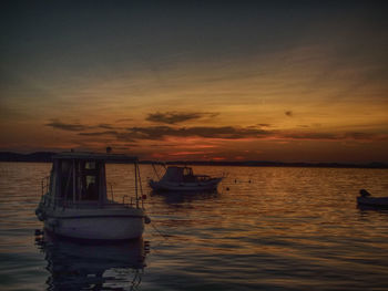 Boats in calm sea at sunset