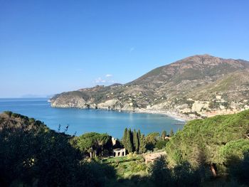 Scenic view of sea and mountains against clear blue sky