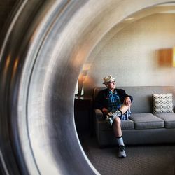 Full length of man sitting on sofa reflecting on mirror