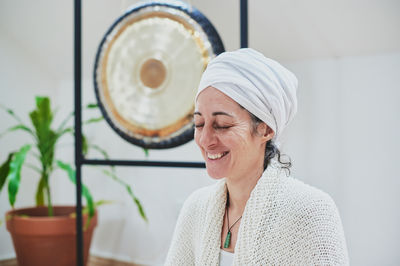 Mature female with closed eyes sitting and practicing yoga at home