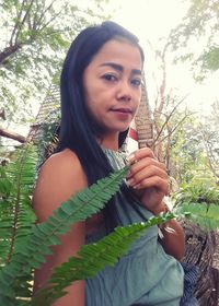 Portrait of smiling young woman holding tree