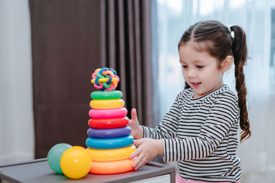 Girl playing with multi colored toys at home