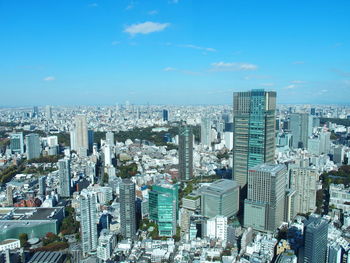 High angle view of modern buildings in city against blue sky