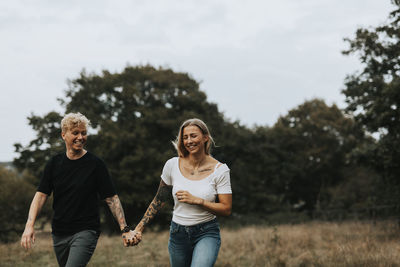 Full length of smiling man and woman against trees