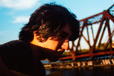 Portrait of young man looking away against sky