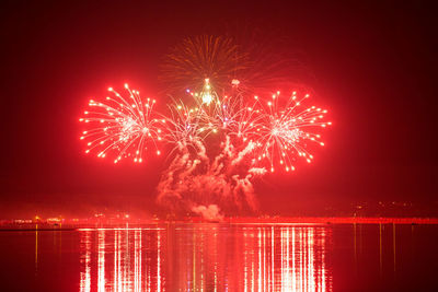 Firework display over lake at night