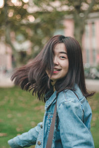 Side view portrait of cheerful woman with tousled hair at park