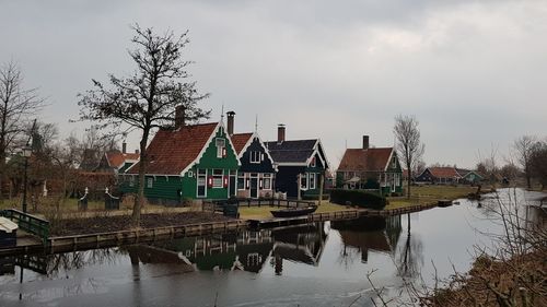 Reflection of houses on canal against cloudy sky 