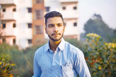 Young man standing against plants 