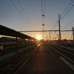 Railroad station platform against clear sky at sunset