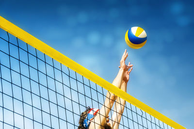 Low angle view of man playing volleyball against blue sky