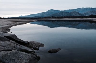 Scenic view of sea by mountains against sky