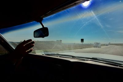 Cropped hand of person against windshield in car