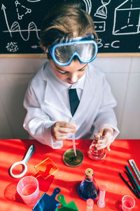 High angle view of boy doing scientific experiment on table in classroom