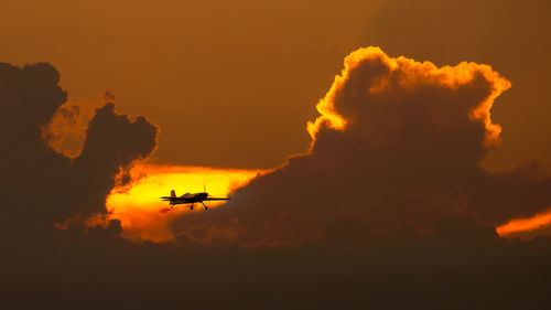 Low angle view of silhouette airplane against sky during sunset
