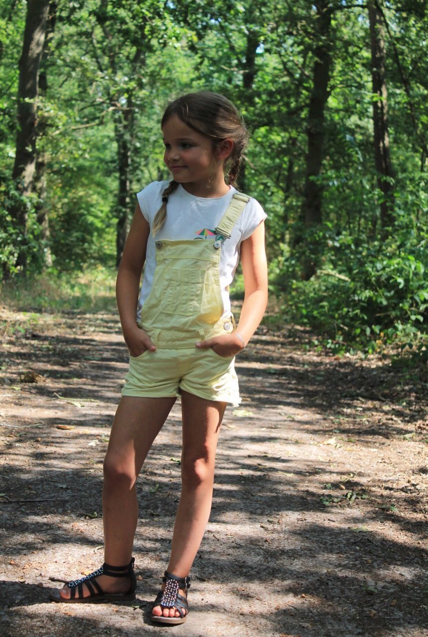 FULL LENGTH OF A GIRL STANDING BY TREE