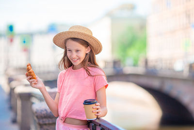 Portrait of smiling woman holding hat in city