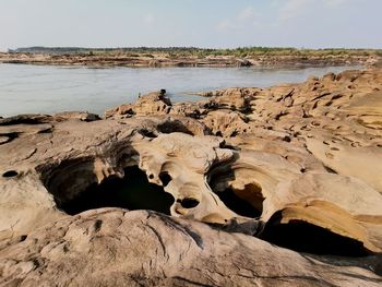 Scenic view of rocks on shore against sky