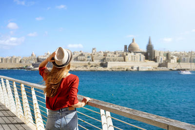 Visiting southern europe. traveler girl walking along malta promenade with valletta cityscape.