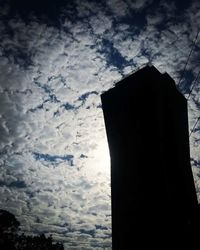 High section of silhouette built structure against clouds