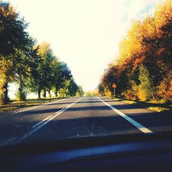 Road amidst trees against sky seen through car windshield