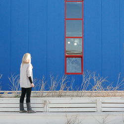Rear view full length of woman standing against blue wall