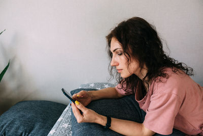 A young brunette woman is resting at home and talking on a smartphone