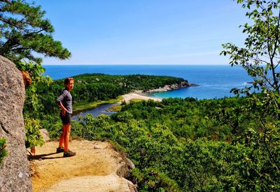 Rear view of man walking by sea against clear sky