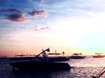 Sailboats in sea at sunset