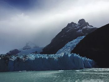 Scenic view of sea by mountain against sky