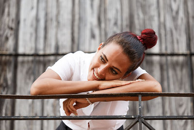 Portrait of young woman leaning against railing