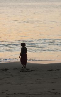 Man on beach against sky during sunset