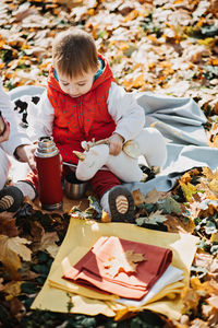 Little cute girl drinks tea from a thermos in the autumn park. cute little toddler baby with