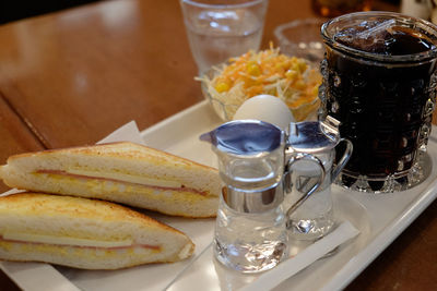 Close-up of sandwich with iced coffee with water in plate