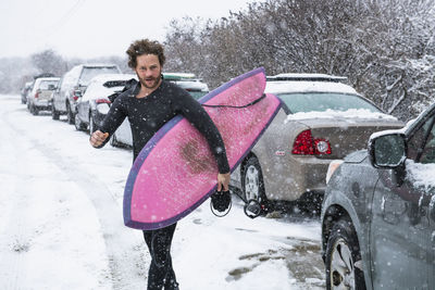 Man preparing to go surfing during winter snow