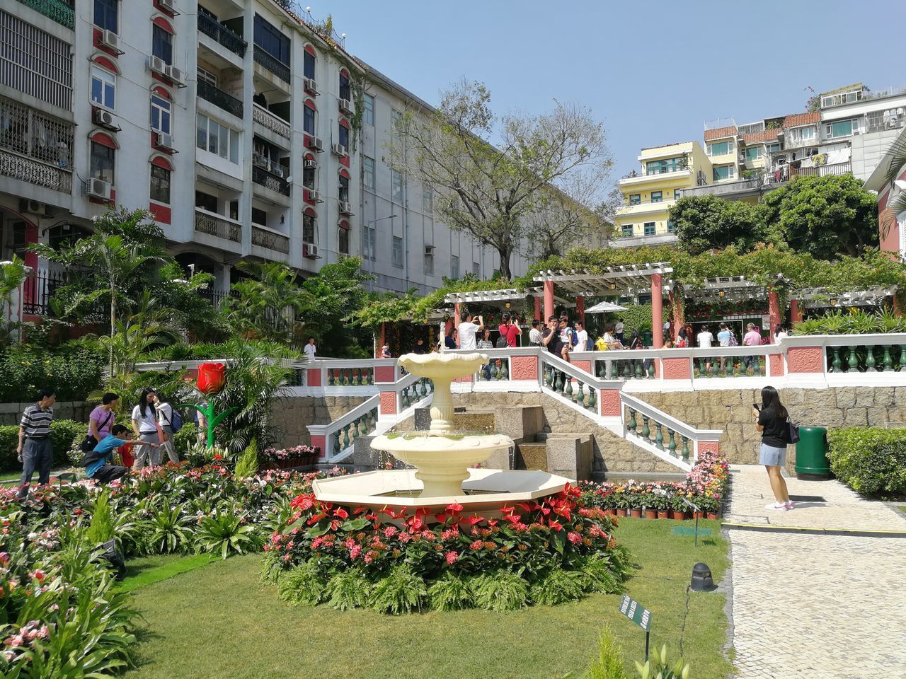 PEOPLE BY SWIMMING POOL IN CITY AGAINST BUILDINGS