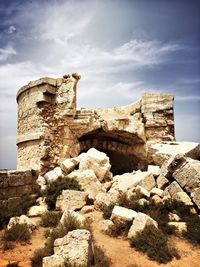 Stone wall with rock formation against sky