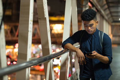 Young man looking at illuminated railing