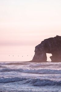 Scenic view of sea and cliff against clear sky