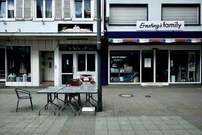 Chairs and tables at sidewalk cafe in city