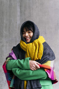 Smiling woman wearing warm clothing wrapped in blanket