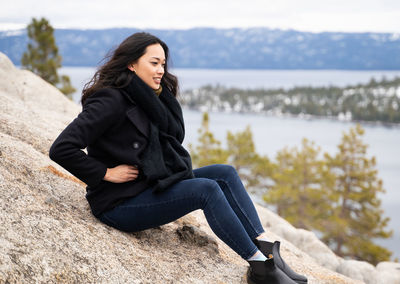 Young woman looking away while sitting on rock