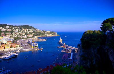 High angle view of buildings by sea against blue sky