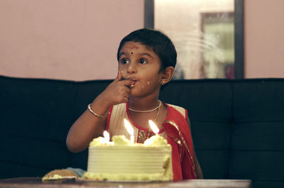 Girl eating birthday cake while sitting at home