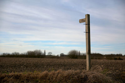 Wooden post on field against sky