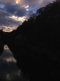 Silhouette trees by lake against sky during sunset