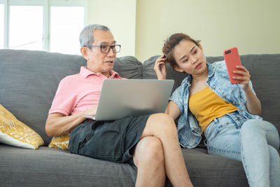 Friends sitting on sofa at home