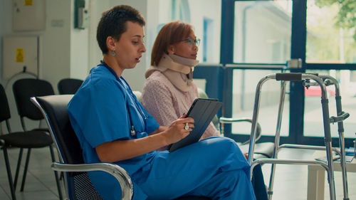 Side view of young woman using mobile phone while sitting in gym